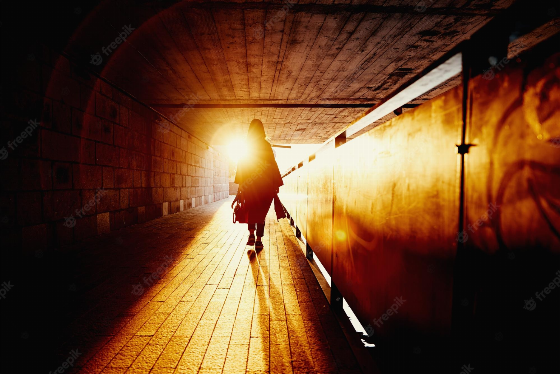 Vista trasera de la silueta de la mujer en el túnel con rayos de sol al  atardecer mujer caminando sola en la calle de la ciudad | Foto Premium